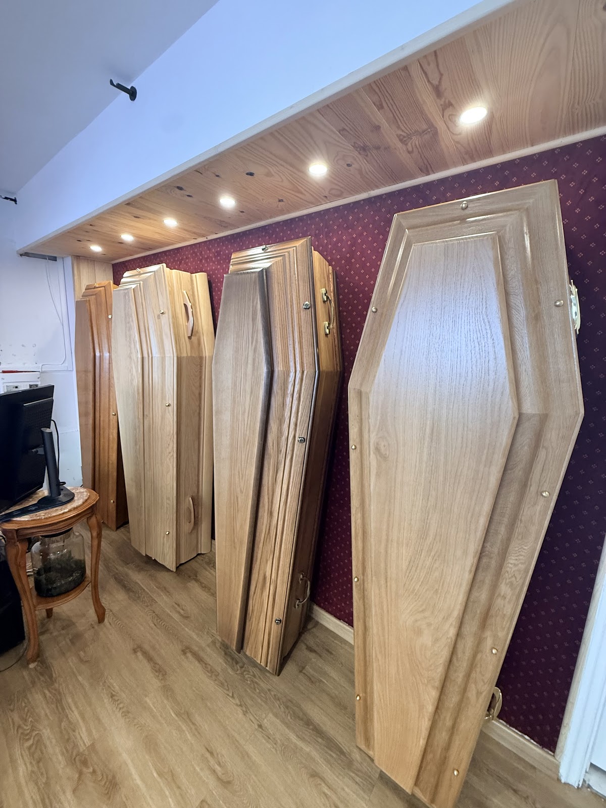 Salon avec cercueils en bois alignés, plafond bois et éclairage